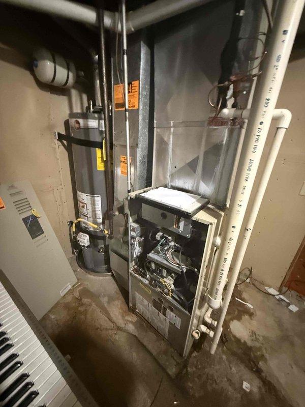 Responded to service call for air conditioning system not cooling properly with reported squeaking noise. Upon inspection, diagnosed failing blower motor and fouled evaporator coil on 2009 system utilizing R22 refrigerant. Presented repair options and full system replacement estimates given age of equipment and obsolete refrigerant type. Documented equipment condition with photographs showing furnace, air handler assembly, and mechanical room installation.