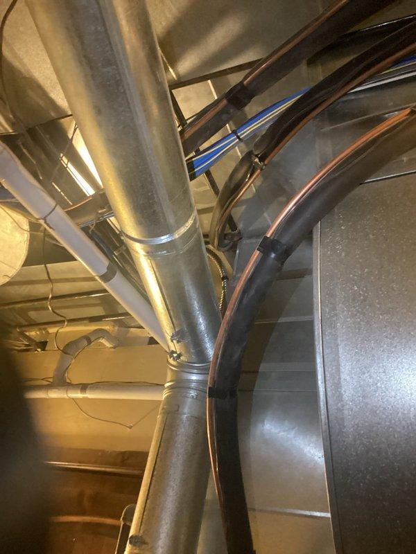 Responded to no cooling complaint on residential property with dual HVAC system configuration. Evaluated 21-year-old system with 16-year-old air conditioning components utilizing two furnaces, two 3-ton evaporator coils, and single outdoor condenser. Identified frozen evaporator coil on right system with failed metering device causing improper refrigerant flow and inadequate cooling performance. Documented moisture accumulation on ductwork and refrigerant lines indicating active system malfunction. Assessed secondary lower-level furnace system also at end of service life. Provided ballpark replacement estimates for both complete dual system replacement and single system replacement options due to age and condition of equipment beyond economical repair.