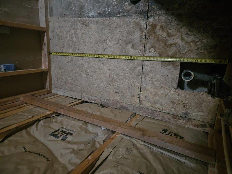 Responded to bathroom remodeling project for plumbing and electrical estimate in upstairs bathroom. Assessed existing plumbing infrastructure including floor drain assembly with accumulated debris, exposed floor joists with insulation, and existing drainage system with PVC piping. Documented current conditions of concrete floor area showing significant wear and staining around drain opening, measured existing pipe locations and clearances for future fixture installation planning. Provided comprehensive evaluation of basement/crawl space plumbing access points and drainage configuration to support upcoming bathroom renovation work.