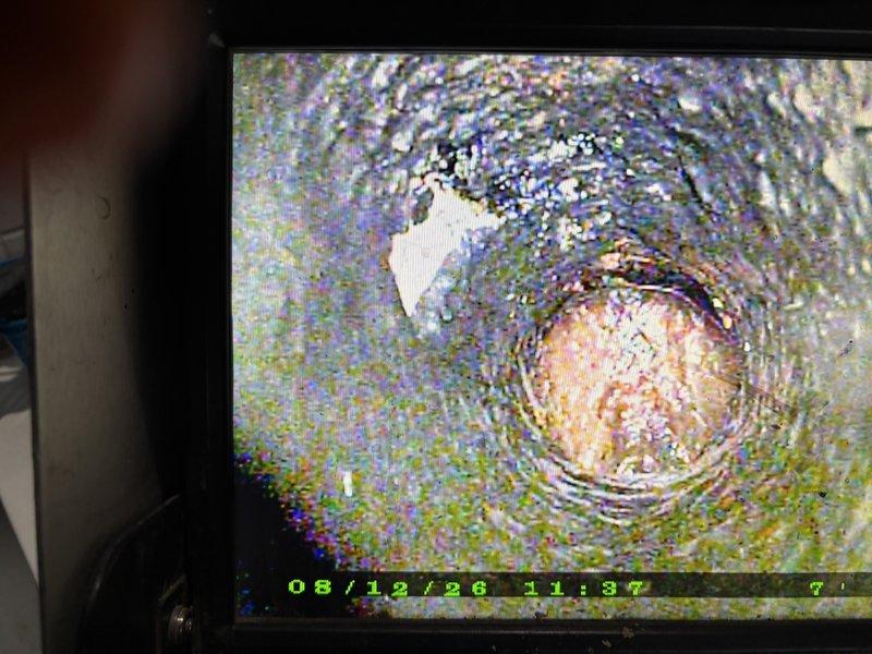 Responded to residential drain service call for single fixture blockage. Performed video camera inspection of drain line, revealing significant mineral deposits, scale buildup, and biological growth on interior pipe walls. Inspection identified deteriorated pipe condition with visible corrosion and discoloration throughout the line. Documented damaged concrete floor section surrounding drain access point, showing structural deterioration with radiating cracks and moisture damage indicative of long-term drainage issues.