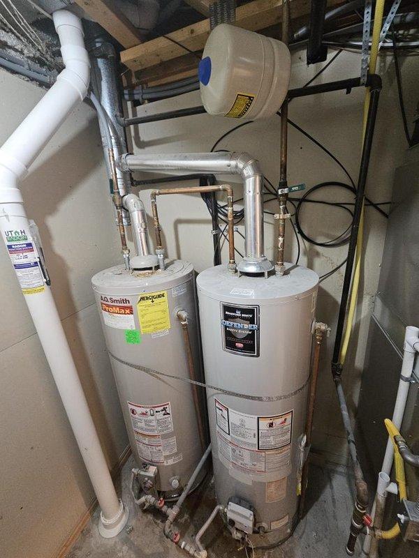Replaced failed 50-gallon gas water heater that was over 20 years old and leaking from the bottom. Installed new A.O. Smith ProMax gas water heater in basement utility area alongside existing secondary unit in dual-tank configuration. Connected copper supply and discharge piping to integrate new unit with existing plumbing system. Installed PVC venting per manufacturer specifications and local code requirements. Connected gas line and verified proper operation. Tested system pressure and confirmed all connections leak-free. System operational with adequate hot water capacity restored.