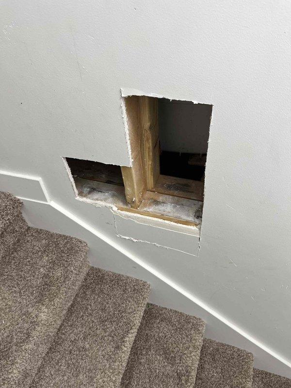 Responded to plumbing fixture issue requiring access to under-floor drainage system. Created access openings in interior wall to expose concealed plumbing infrastructure, revealing black ABS/PVC drainage pipes with fittings running horizontally through floor joists. Assessed condition of existing drainage components and structural framing in confined crawl space area. Completed necessary fixture repair/replacement work with access through wall cavity and subfloor area.