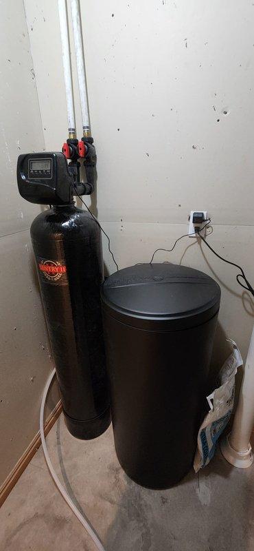 Removed two existing tanked water heaters from service, shut off water supply, drained system, and properly disposed of old units. Installed Navien NPE-240A2 tankless water heater with complete gas and water repiping to support new configuration, including 3-way service isolation valves for maintenance access. Vented exhaust through existing roof flue cap, routed condensate line to drain, and verified all connections for proper operation. Installed 64,000 grain Sentry 2 water softener on existing loop with digital control head, brine tank, and five bags of salt. Added mixing valve to reintroduce 2 grains of hardness into softened water to eliminate slippery water feel. Routed discharge line to drain and tested complete system for proper flow, temperature control, and water quality performance.