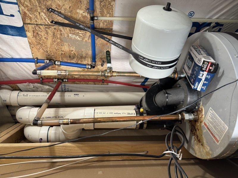 Responded to water heater leak causing basement flooding. Installed new water heater system with expansion tank, electronic circulation pump with digital display, and complete piping assembly including PEX distribution lines, copper supply connections, and PVC drain lines. Connected brass manifold valve assembly for multi-zone water distribution and wired electrical connections for pump operation. System tested and confirmed operational with no active leaks detected.