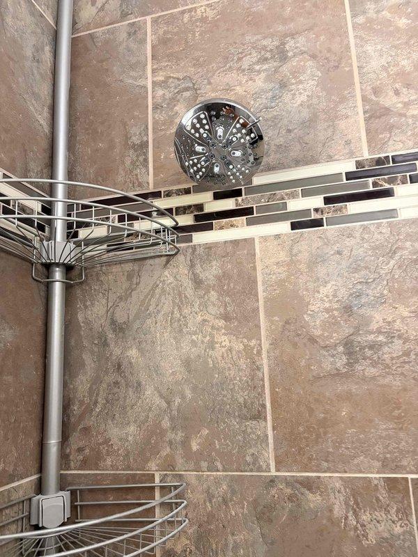 Installed Moen single-handle Posi-Temp pressure-balancing shower valve with remodel trim kit in chrome finish. Completed rough-in valve installation and mounted trim components to existing tiled shower wall, ensuring proper alignment with decorative tile border and existing shower fixtures. Tested system for proper temperature control and verified no leaks at connections.