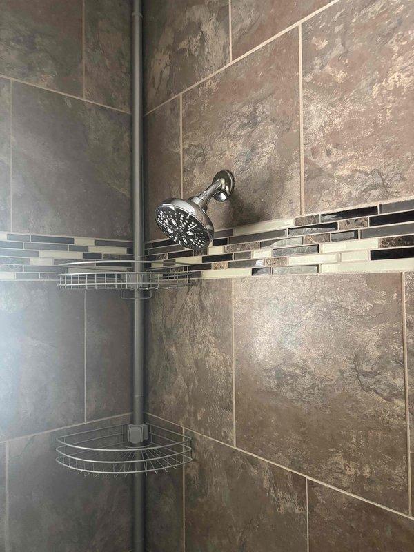 Installed Moen single-handle Posi-Temp pressure-balancing shower valve with remodel trim kit in chrome finish. Completed rough-in valve installation and mounted trim components to existing tiled shower wall, ensuring proper alignment with decorative tile border and existing shower fixtures. Tested system for proper temperature control and verified no leaks at connections.