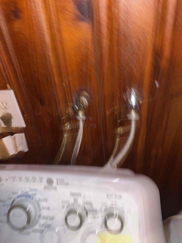 Responded to broken washing machine valve in laundry room. Inspected existing brass shut-off valve with cross-handle, which was inoperable and preventing installation of new washer/dryer unit. Replaced faulty valve with new quarter-turn shut-off valve, installed braided stainless steel flex supply line, tested connections for leaks, and verified proper operation of shut-off mechanism to allow for appliance installation.