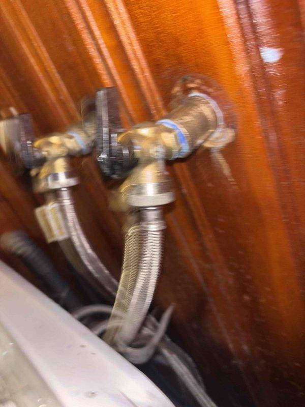Responded to broken washing machine valve in laundry room. Inspected existing brass shut-off valve with cross-handle, which was inoperable and preventing installation of new washer/dryer unit. Replaced faulty valve with new quarter-turn shut-off valve, installed braided stainless steel flex supply line, tested connections for leaks, and verified proper operation of shut-off mechanism to allow for appliance installation.
