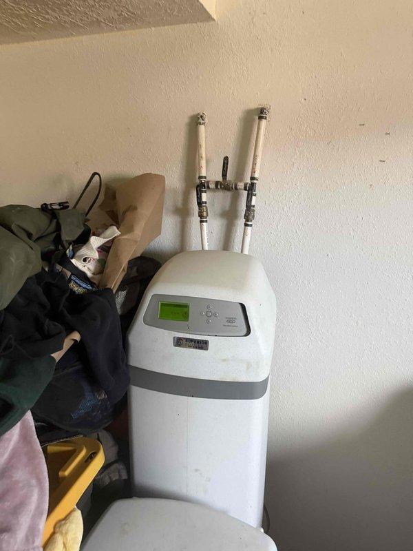 Responded to service call for water softener system maintenance in basement utility area. Upon arrival, inspected EcoWater brand water softening unit consisting of mineral tank with digital control head and separate brine tank. Confirmed brine tank was depleted of salt media, which had been empty for an undetermined period. Assessed system components including control valve, resin tank, and brine tank for proper operation and potential complications from extended operation without salt. Verified plumbing connections and bypass valves were functioning correctly. Replenished brine tank with appropriate water softener salt to restore system functionality. Programmed control head settings and initiated regeneration cycle to ensure proper ion exchange process resumption. Advised on recommended salt levels and monitoring procedures to prevent future depletion. System operational upon completion of service.