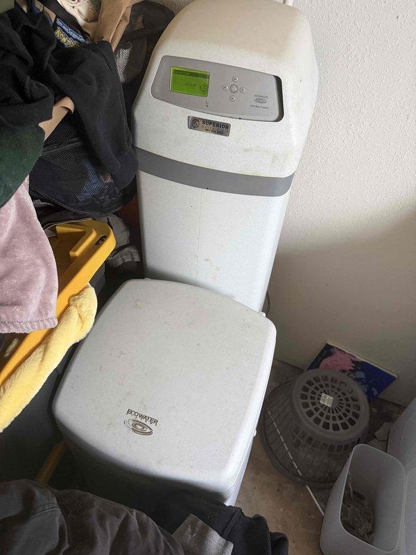 Responded to service call for water softener system maintenance in basement utility area. Upon arrival, inspected EcoWater brand water softening unit consisting of mineral tank with digital control head and separate brine tank. Confirmed brine tank was depleted of salt media, which had been empty for an undetermined period. Assessed system components including control valve, resin tank, and brine tank for proper operation and potential complications from extended operation without salt. Verified plumbing connections and bypass valves were functioning correctly. Replenished brine tank with appropriate water softener salt to restore system functionality. Programmed control head settings and initiated regeneration cycle to ensure proper ion exchange process resumption. Advised on recommended salt levels and monitoring procedures to prevent future depletion. System operational upon completion of service.