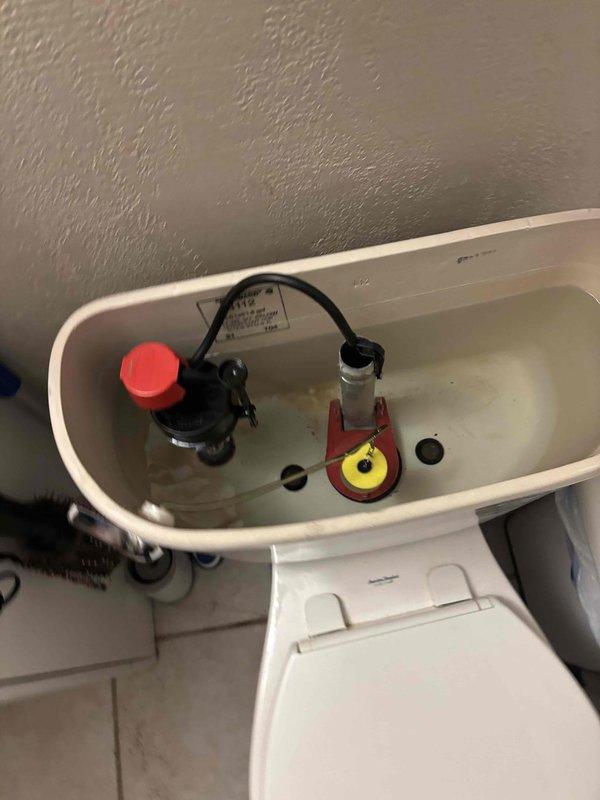 Responded to plumbing callback for toilet tank not filling and water running continuously from previous unresolved service visit. Inspected internal tank components including fill valve with red cap, flush valve assembly, and flapper mechanism. Adjusted and serviced fill valve and flapper assembly to restore proper tank filling function and eliminate continuous water flow.