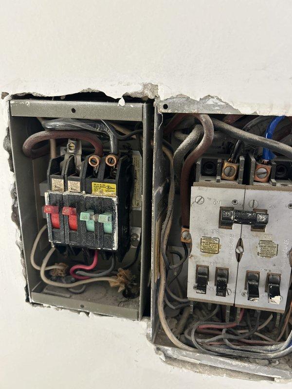 Responded to storm-related electrical damage at service entrance where main power lines enter the residence at the eave. Upon arrival, inspected exterior damage to service entry point and assessed existing electrical panel configuration, which consisted of older fuse box and breaker panel installation with visible deterioration to surrounding wall structure. Documented conditions with photographs showing compromised service entrance equipment and aged interior panel components requiring repair to restore safe, code-compliant electrical service.