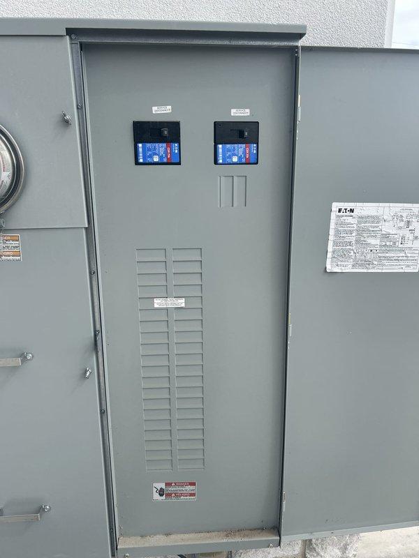 Completed comprehensive Green Shield electrical inspection of outdoor main electrical service panel. Inspected Eaton-branded electrical distribution equipment including dual digital display meters with blue backlighting showing proper operational readouts. Verified ventilation louvers functioning correctly, confirmed all panel mounting hardware secure, and ensured all warning labels properly affixed and legible. Documented panel condition with photos showing all components in clean, functional condition with no visible damage or safety concerns.