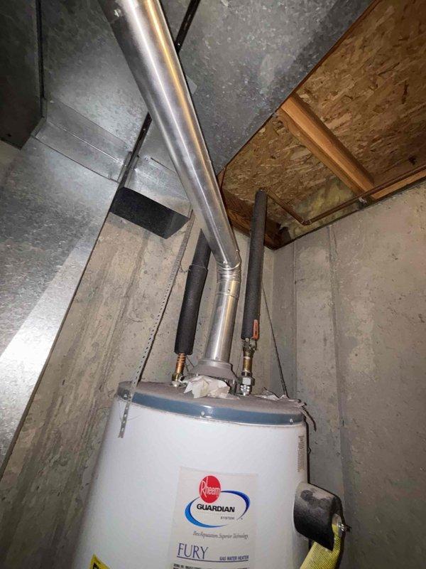 Responded to a no hot water call for a 6+ year old Rheem Guardian Fury tank-style water heater located in the basement. Diagnosed pilot light failure where pilot would not remain lit after ignition, indicating a faulty thermocouple or gas control valve issue. Inspected unit, confirmed proper venting and gas supply connections, and documented existing installation with black foam pipe insulation on water lines and standard exhaust configuration.