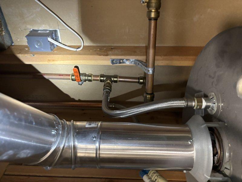 Responded to service call for active water heater leak at residential rental property. Upon arrival, inspected 11-year-old tank-style water heater located in basement mechanical space. Confirmed active leak originating from tank assembly. Assessed existing copper supply line configuration with brass fittings, orange-handled shutoff valve, and flexible braided supply connections. Evaluated overall system condition including visible patina on copper piping and existing plumbing infrastructure. Documented installation setup showing horizontal positioning beneath floor joists with wooden structural support members overhead. Photographed affected equipment and surrounding plumbing connections for record. Provided customer with upfront pricing options for repair versus replacement given age of unit exceeding typical service life expectancy. Recommended full water heater replacement due to tank age and active leak condition, as tank failures are typically not repairable and unit has surpassed