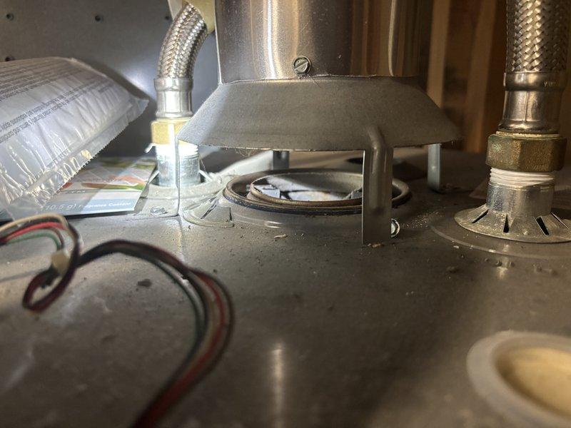 Responded to service call for active water heater leak at residential rental property. Upon arrival, inspected 11-year-old tank-style water heater located in basement mechanical space. Confirmed active leak originating from tank assembly. Assessed existing copper supply line configuration with brass fittings, orange-handled shutoff valve, and flexible braided supply connections. Evaluated overall system condition including visible patina on copper piping and existing plumbing infrastructure. Documented installation setup showing horizontal positioning beneath floor joists with wooden structural support members overhead. Photographed affected equipment and surrounding plumbing connections for record. Provided customer with upfront pricing options for repair versus replacement given age of unit exceeding typical service life expectancy. Recommended full water heater replacement due to tank age and active leak condition, as tank failures are typically not repairable and unit has surpassed