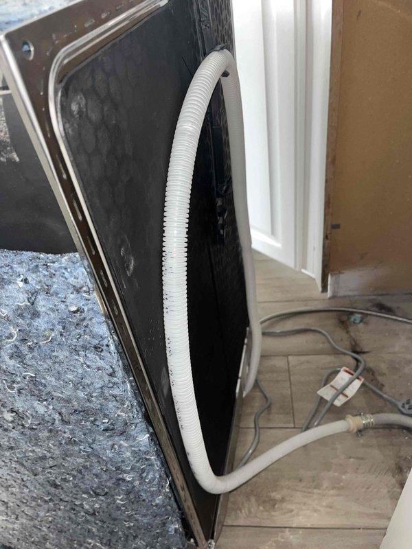 Corrected improper dishwasher drain installation and replaced incompatible supply line in kitchen. Dishwasher was pulled from cabinet space, existing drainage connection was removed and reinstalled to proper specifications, and water supply line was replaced with correct fitting to ensure proper connection to appliance inlet. Unit was repositioned and secured under counter with all connections verified for proper operation.