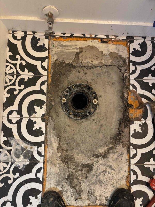 Jackhammered and removed concrete and decorative tile flooring to expose the closet 90 drain fitting. Installed new toilet flange with proper mounting and sealing. Re-poured concrete underlayment in the excavated area to restore proper floor elevation. Cut out existing 3-inch ABS 90 degree elbow and flange assembly. Reset toilet on new flange and performed leak testing to verify proper seal and drainage. Installed new emergency shutoff valve for toilet water supply line. Vanity disconnection was performed as needed to facilitate access to plumbing connections. Drywall remained open for inspection and final finishing work. Tile replacement was not included in scope of work.