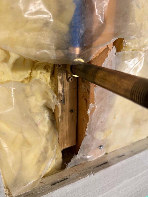 Responded to warranty recall for shower fixture installation and tub hot water issue. Accessed plumbing cavity through wall opening to locate and address mixing valve assembly with copper piping. Reset tub fixture connections and verified proper hot water delivery to resolve temperature control problem.