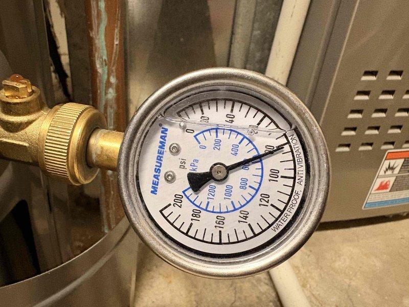 Responded to a known leak originating from kitchen sink plumbing that caused water damage in the basement furnace room. Inspected broken pipe in furnace room area and assessed 1990-91 era plumbing system. Additionally evaluated minor intermittent leak at bathroom sink fixture showing hard water mineral buildup and staining on shower valve escutcheon. Documented system pressure readings and overall plumbing conditions in mechanical room area.