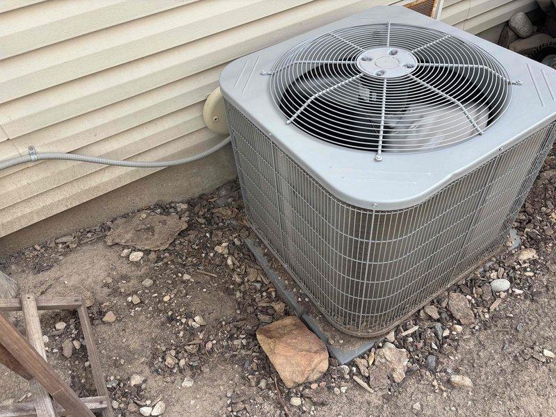 Completed membership-included air conditioning tune-up on ground-mounted condensing unit with indoor air handler located in basement. Performed standard preventive maintenance procedures including system performance testing with digital multimeter, inspection of condenser coil fins, and verification of operational parameters. Scheduled follow-up visit to address drain line issue and unit leveling concerns requiring additional service work.