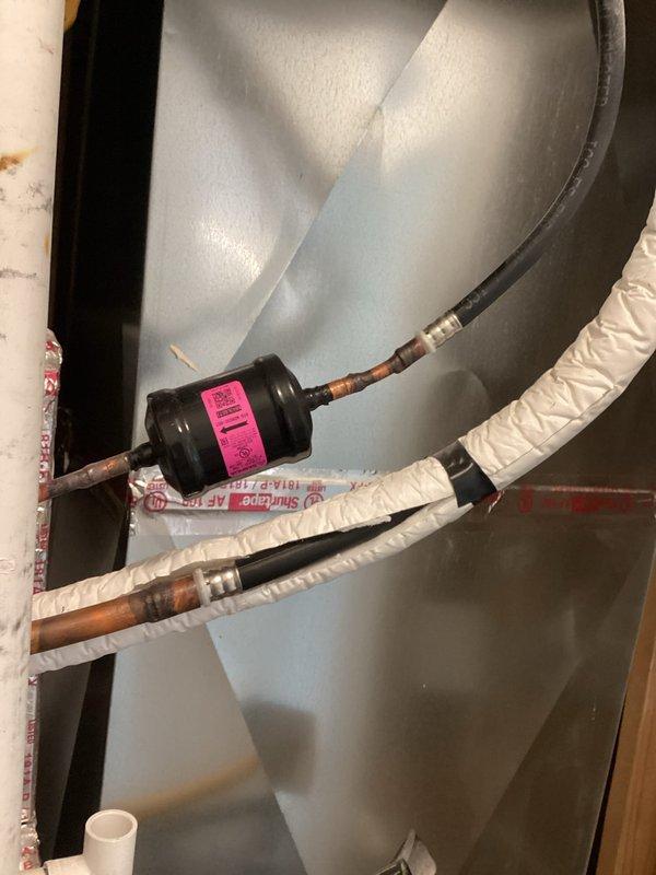 Completed routine membership maintenance inspection on two 6-year-old air conditioning systems with condensers located on back side of property and air handlers in basement and upstairs locations. Performed comprehensive system evaluation including refrigerant line inspection, capacitor testing showing 63.3 MFD reading, and filter-drier component assessment. Noted oxidation and discoloration on copper refrigerant lines with existing foam insulation wrap. Both systems operational with no reported issues at time of service.