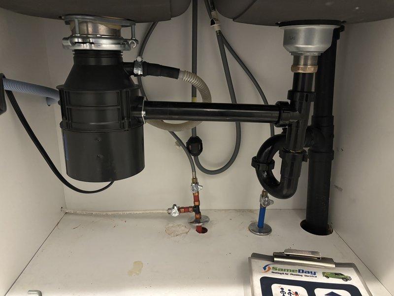 Responded to kitchen sink drainage issue where left basin was not draining and standing water with heavy sediment accumulation was present. Inspected double-basin sink with dual garbage disposal configuration and P-trap assemblies beneath. Cleared blockage in drainage system, restoring proper flow to affected fixture.