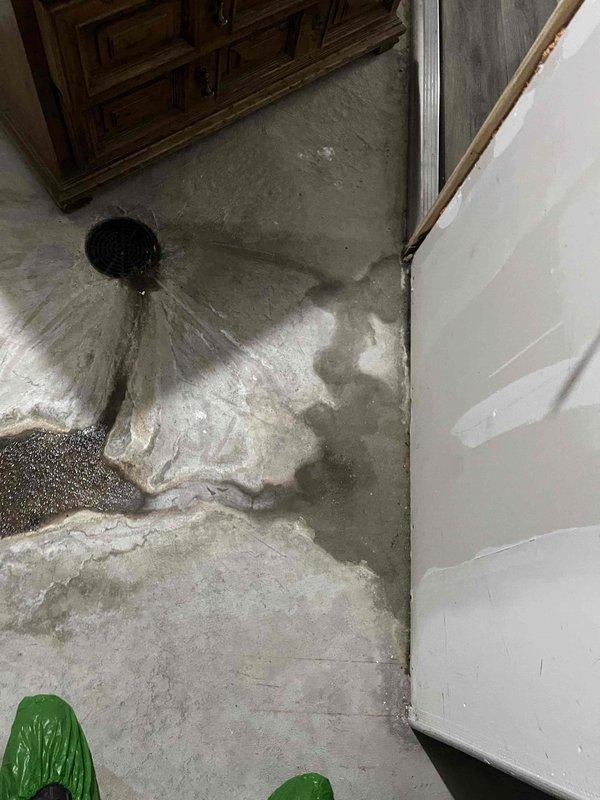 Responded to reported water leak with suspected dishwasher source causing wall and floor damage. Upon arrival, found significant water accumulation on basement concrete floor with active pooling near floor drain and moisture damage extending across multiple areas. Documented extensive water intrusion affecting flooring and baseboards, with visible saturation patterns indicating ongoing leak requiring source identification and remediation.
