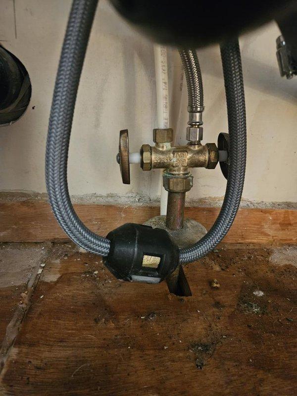 Completed kitchen faucet installation and inspected water heater plumbing connections. Verified pressure gauge reading at approximately 75 psi and confirmed proper operation of brass T-valve assembly with flexible supply lines. All connections secured and system tested for leaks.