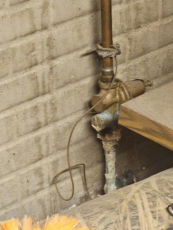 Responded to no water flow issue at residential property where city confirmed water flowing at exterior meter but no water reaching interior faucets. Upon inspection, located severely corroded brass backflow preventer and deteriorated copper piping at main water service entry point on exterior wall. The backflow preventer exhibited heavy oxidation, mineral buildup, and structural degradation that was obstructing water flow into the home's plumbing system. Assessed the corroded valve assembly and compromised pipe sections that required replacement to restore water service to all interior fixtures.