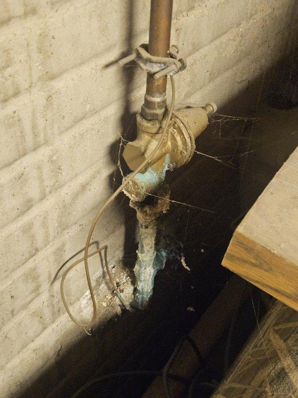 Responded to no water flow issue at residential property where city confirmed water flowing at exterior meter but no water reaching interior faucets. Upon inspection, located severely corroded brass backflow preventer and deteriorated copper piping at main water service entry point on exterior wall. The backflow preventer exhibited heavy oxidation, mineral buildup, and structural degradation that was obstructing water flow into the home's plumbing system. Assessed the corroded valve assembly and compromised pipe sections that required replacement to restore water service to all interior fixtures.