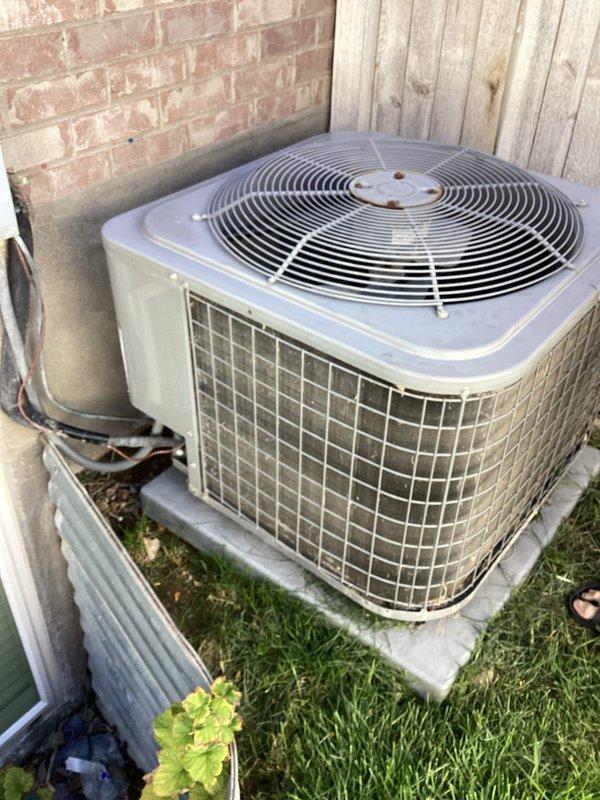 Responded to no cooling complaint on 10+ year old residential air conditioning system. Upon arrival, located outdoor condenser unit in backyard and performed diagnostic testing using digital multimeter to check electrical values and system operation. Inspected older model condenser unit with weathered casing, verified proper placement on concrete pad, and assessed overall equipment condition including exposed electrical connections and conduit. Documented system readings and equipment status with photos showing diagnostic measurements and unit configuration.