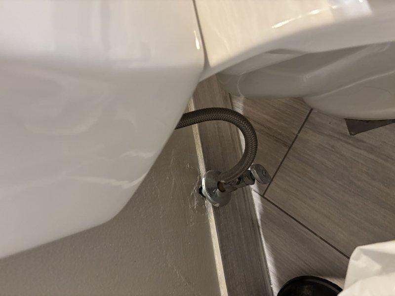 Responded to emergency call for active leak originating from master bathroom with water penetrating to lower level. Inspected bathroom fixtures, water supply lines, and surrounding areas to identify source of leak. Located issue at toilet water supply connection where braided supply line showed signs of failure at wall mounting point, causing water to seep through flooring and ceiling below.