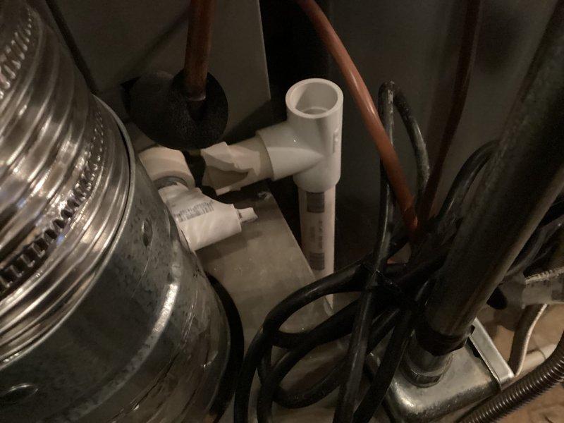 Responded to no cooling complaint on residential HVAC system aged 6-9 years with basement furnace and exterior condensing unit. Inspected system components including condensate drainage assembly, PVC piping connections, and mechanical equipment installation. Documented equipment condition and configuration with photographic records of furnace, water heater, expansion tank, and associated plumbing connections in basement mechanical room.