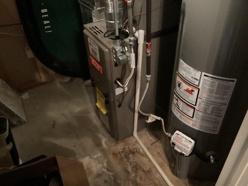 Responded to no cooling complaint on residential HVAC system aged 6-9 years with basement furnace and exterior condensing unit. Inspected system components including condensate drainage assembly, PVC piping connections, and mechanical equipment installation. Documented equipment condition and configuration with photographic records of furnace, water heater, expansion tank, and associated plumbing connections in basement mechanical room.