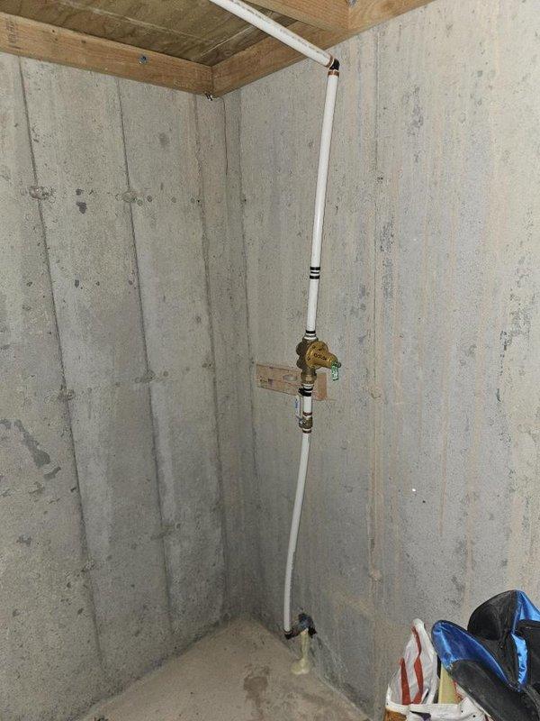 Completed installation of two new hose bibs per previously provided estimate. Assessed placement options and addressed installation challenges related to existing plumbing configuration in basement utility area. Installed new hose bib with brass valve fitting and white PVC supply line, securing valve to concrete foundation wall with wooden mounting block for proper support. Routed supply piping vertically along basement corner from floor to ceiling joists, ensuring proper connection to existing water supply system. Second hose bib installation completed in finished living space with consideration for interior wall penetration and coordination with existing HVAC floor register location. All installations tested for proper operation and verified no leaks at connections and valve seats.