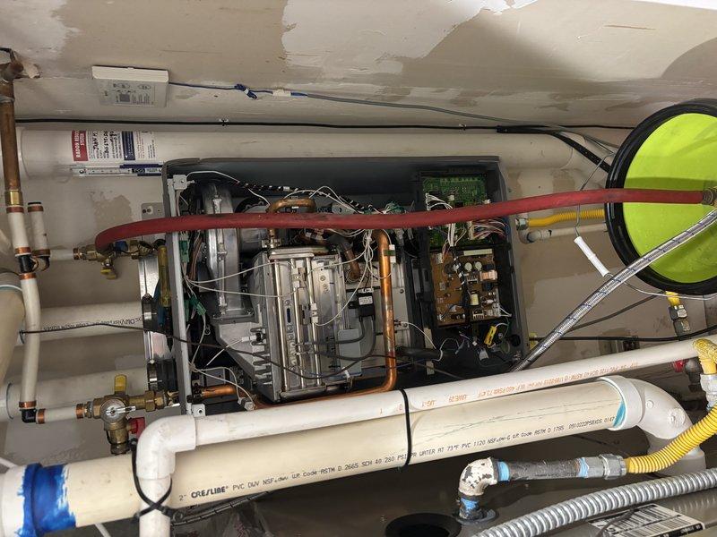 Completed non-member plumbing inspection on two approximately 6-year-old tankless water heaters requiring maintenance flushing services. Inspected first unit located in crawlspace and second unit positioned in second-floor utility closet, documenting equipment serial numbers, AHRI certification labels, and overall system conditions including visible piping configurations, copper supply lines with brass valves, PVC discharge lines, and electrical connections. Photographed equipment nameplates showing Nortek America Corporation manufacturing details and assessed both installations for proper venting, gas line connections, and general operational readiness prior to performing scheduled flush maintenance.