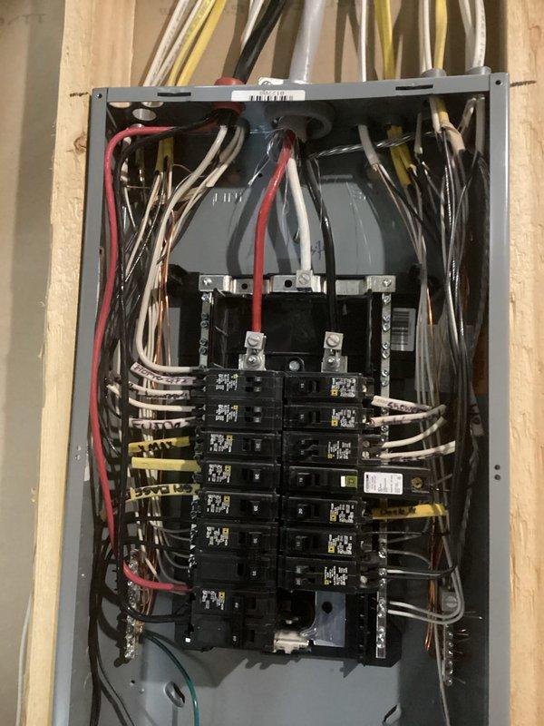 Conducted on-site evaluation for electric vehicle charger installation in garage. Assessed existing electrical panel capacity and circuit breaker configuration to determine feasibility of dedicated EV charging circuit. Photographed main service panel showing current breaker layout, available spaces, and circuit directory indicating existing EV charger notation, suggesting previous planning or partial installation. Identified necessary components and installation requirements for completing Level 2 EV charging station connection.