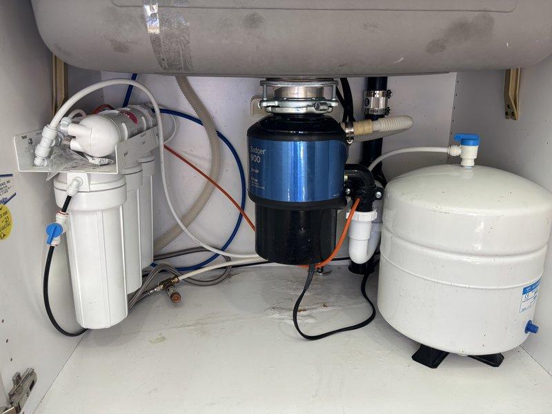 Installed customer-supplied garbage disposal unit with complete drain system reconfiguration, including installation of 2" x 1-1/2" x 1-1/2" sanitary tee, 2" coupling, and 1-1/2" no-hub band to accommodate new disposal configuration. Installed pull-down kitchen faucet with brushed stainless steel finish and reconnected reverse osmosis system with new 1/4" and 3/8" compression fittings, stiffeners, and ferrules. All fixtures tested and confirmed operational with no leaks detected.
