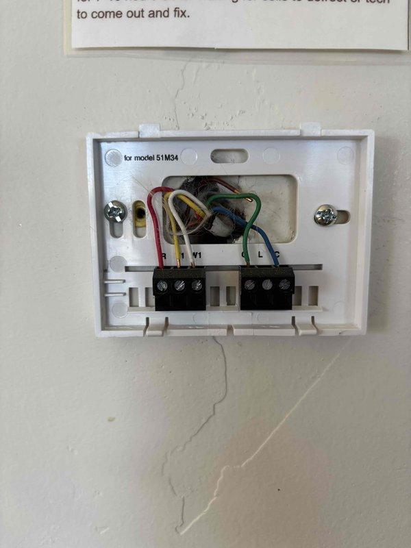 Completed HVAC Cool 5-9 maintenance inspection at condo property with outdoor condensing unit and basement furnace installation. Inspected existing Lennox programmable thermostat, documented current wiring configuration showing standard color-coded connections (red, yellow, green, blue) at terminal blocks, and verified thermostat operation displaying 76°F at time of service. Provided WiFi-capable thermostat for potential upgrade consideration at rental property.