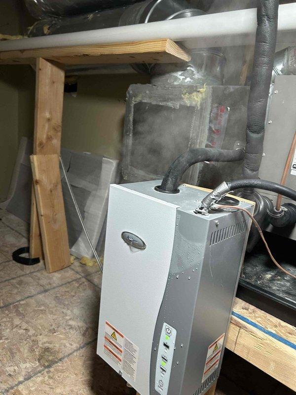 Completed installation of outdoor temperature sensor for humidifier system integration. Sensor was properly wired and configured to communicate with existing whole-home humidification equipment, ensuring accurate humidity control based on outdoor ambient temperature readings. Documentation photographs of equipment serial numbers were captured for service records.