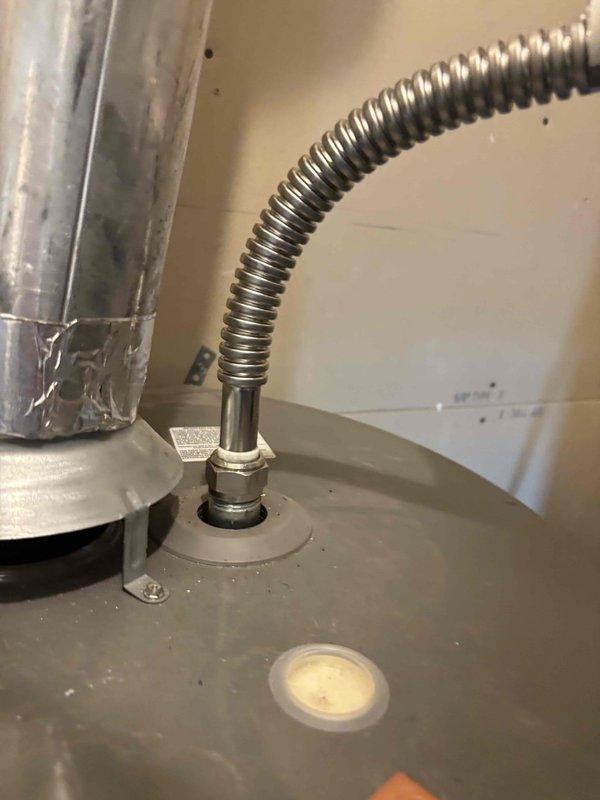 Responded to service call for dual water heater system experiencing water hammer noise and ignition failure. Inspected 6-year-old Rheem 50-gallon tanked unit located in upstairs utility closet that was displaying valve failure error code and failing to relight since April. Diagnosed water hammer issue occurring when hot water fixtures are used simultaneously throughout home. Examined tank interior, flue venting system, and gas valve assembly. Documented condition of installation including flexible gas connector, mounting configuration, and venting penetration through roof assembly. Assessed both water heaters to determine cause of simultaneous fixture operation creating pressure surge and evaluated non-functioning unit's ignition system and gas valve operation per manufacturer specifications.