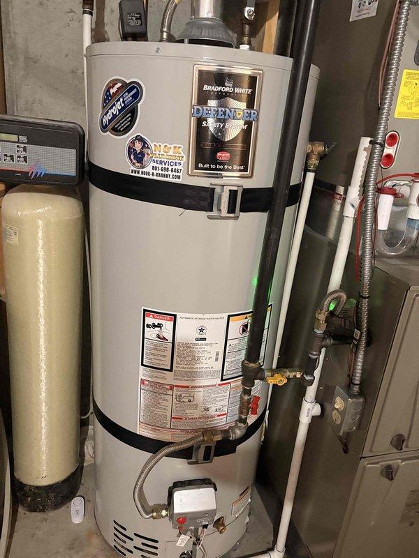 Performed non-member inspection on Bradford White Defender Safety System natural gas water heater located in basement. Completed water heater flush service and inspected anode rod condition as requested by homeowner who recently purchased the property. Unit secured with proper strapping, connected to water softener system via copper and PVC piping, with all safety labels and manufacturer specifications visible and intact.