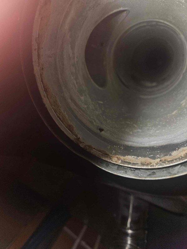 Responded to emergency call for furnace flooding in basement utility room. Upon arrival, found significant water accumulation in and around furnace unit, which was interfering with concurrent electrical work being performed. Inspected HVAC system including furnace, blower motor housing, and associated piping connections. Identified water intrusion issue affecting the heating system operation. Examined condensate drain system, evaporator coil area, and blower assembly to locate source of water discharge. Documented system condition with photos showing furnace installation, gas line connections with red and green valve handles, and interior view of cylindrical blower housing showing dust accumulation and wear patterns. Addressed immediate water issue to allow electrical repairs to proceed safely and prevent further damage to equipment and surrounding area.