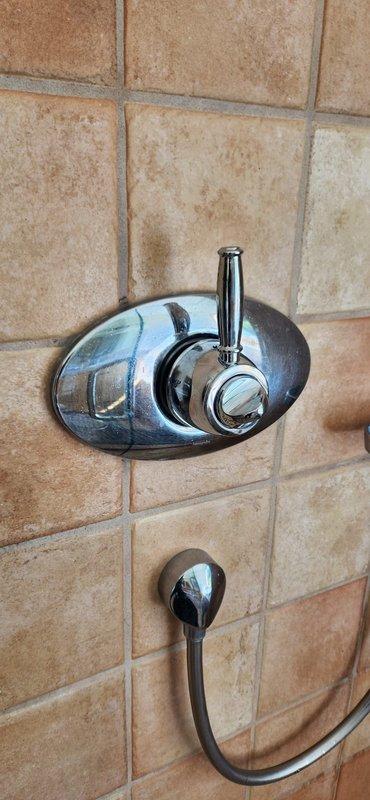 Completed warranty callback for shower valve replacement in master bathroom. Installed special-ordered replacement shower fixture handle and mounting assembly on ceramic tile wall. Installed additional circuit board component (hot button module) to enable app-based control functionality for hot water recirculation system, which was not included in original installation. Corrected water softener drain line positioning, adjusting discharge to properly terminate 3 inches into drain to prevent overflow conditions.