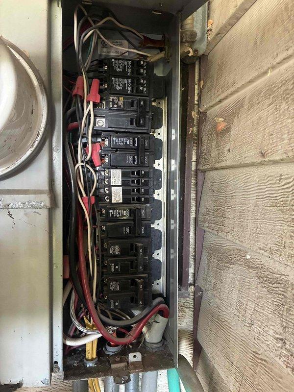 Performed comprehensive electrical inspection throughout the residence in response to reports of sparking outlets and safety concerns. Identified critical code violation where the air conditioning unit was improperly wired into the furnace circuit on an undersized 20-amp breaker instead of the required 25-amp dedicated circuit, causing the breaker to fail and arc. Found no disconnect installed for the AC unit as required by electrical code. Shut off power to the compromised circuit to prevent fire hazard. Inspected and documented electrical panel conditions, noting disorganized wiring, aging components, and multiple code deficiencies. Evaluated outlets and switches in bedrooms, living room, and kitchen as reported. Provided recommendations for installing proper dedicated AC circuit with appropriate amperage breaker, adding required disconnect, and addressing electrical safety concerns throughout the home.