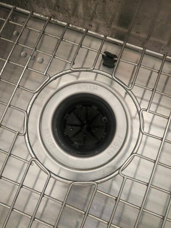 Responded to kitchen sink garbage disposal malfunction where unit was making noise when activated but not running. Upon inspection, diagnosed failed MOEN garbage disposal unit mounted beneath sink basin. Removed defective disposal unit from mounting assembly and installed replacement disposal, reconnecting drain lines and electrical power supply. Tested unit for proper operation and verified all connections were secure with no leaks.
