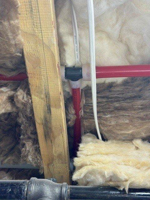 Responded to reported slow drip from plumbing joint in ceiling area near water heater location. Accessed attic space and inspected PEX and PVC piping connections running through insulated ceiling cavity. Performed pressure testing on the system using calibration gauge to identify leak source at pipe fitting junction. Addressed the leaking connection point and verified system integrity upon completion.
