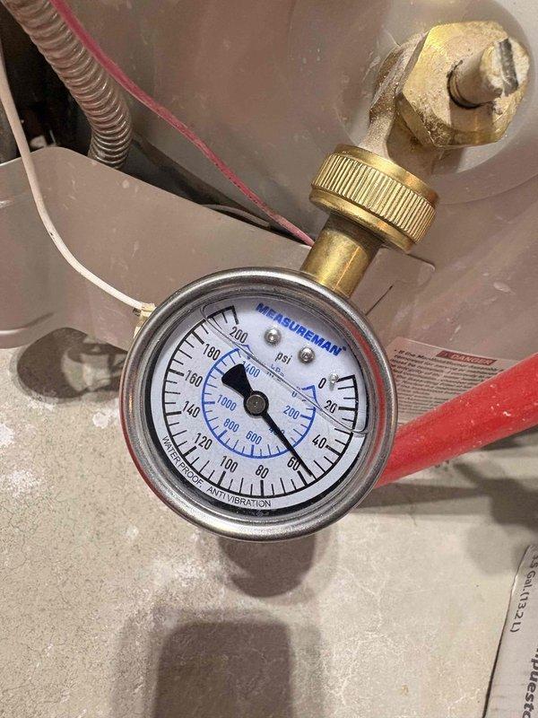 Responded to reported slow drip from plumbing joint in ceiling area near water heater location. Accessed attic space and inspected PEX and PVC piping connections running through insulated ceiling cavity. Performed pressure testing on the system using calibration gauge to identify leak source at pipe fitting junction. Addressed the leaking connection point and verified system integrity upon completion.