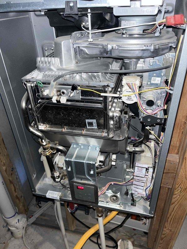Responded to service call for tankless water heater experiencing intermittent cold water delivery during hot water usage. Customer reported cold water interruptions lasting approximately one minute occurring after 3-4 minutes of hot water flow. Previous tankless flush service had been completed without resolving the issue. Performed diagnostic evaluation of tankless unit, including visual inspection of internal components, heat exchanger assembly, gas valve, ignition system, and flow sensor mechanisms. Documented equipment condition through photographic documentation showing burner assembly, combustion chamber, control boards, and associated plumbing connections. Consulted with manufacturer technical support to troubleshoot intermittent temperature fluctuation issue. Provided estimate for alternative solution involving replacement of tankless system with conventional tank-style water heater. Recommended 50-gallon capacity unit based on household occupancy of five residents. Assessed ex